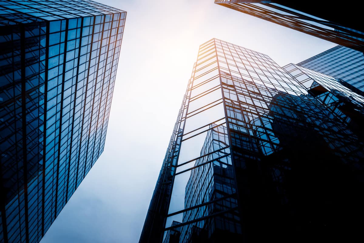 Vista de baixo para cima de dois edifícios corporativos de vidro contra o céu