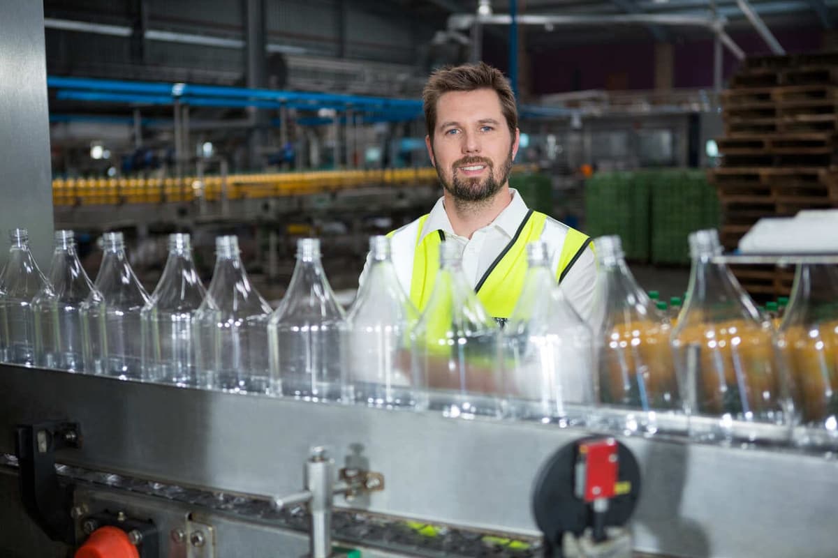 Funcionário de fábrica de embalagens em linha de envase de garrafas