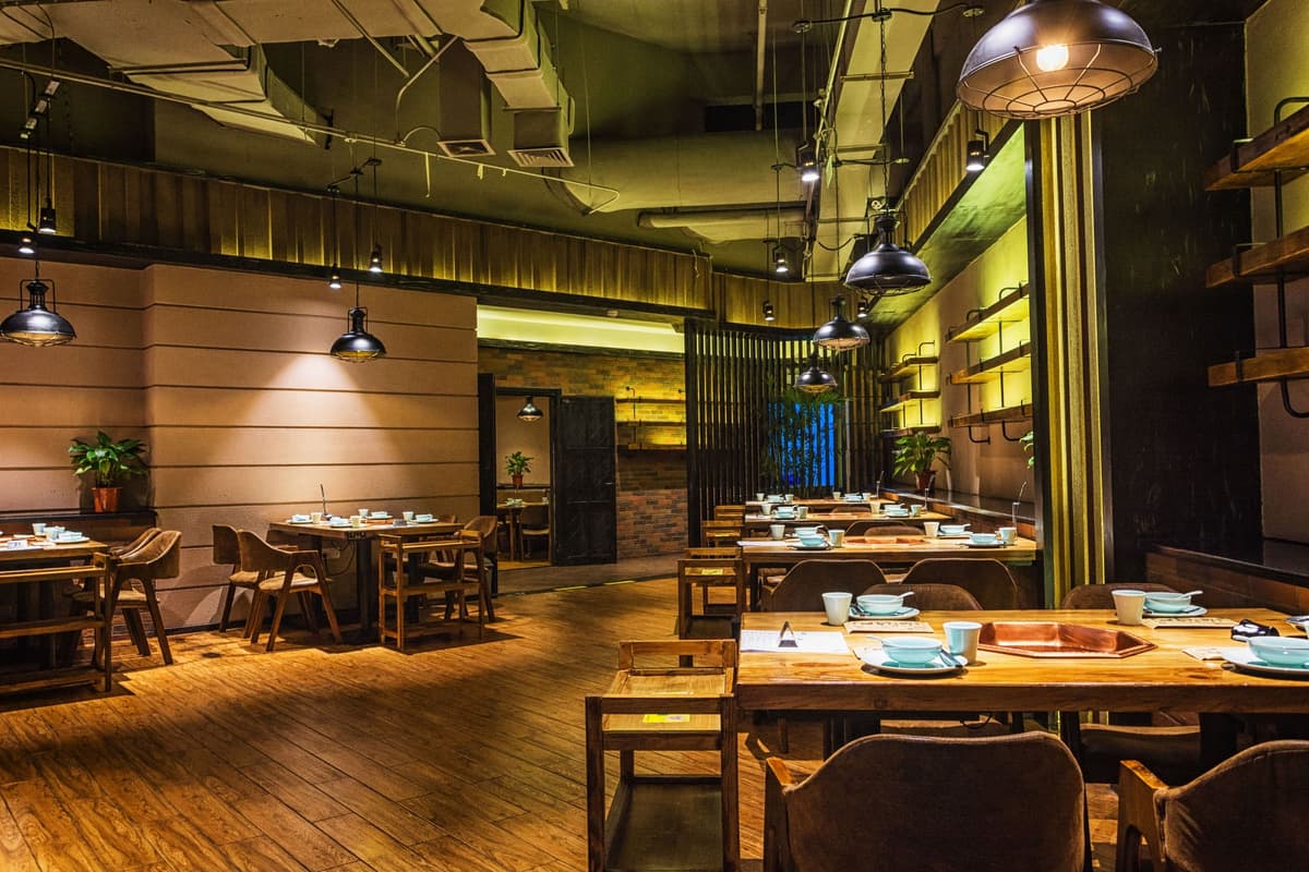 Salão de restaurante decorado com mesas de madeira e iluminação aconchegante